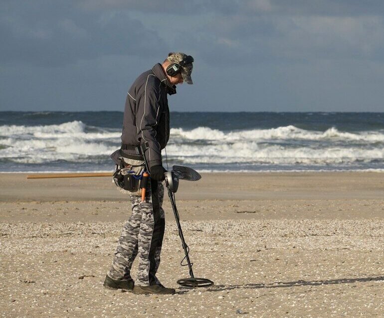 man in black jacket and black pants holding black dslr camera on beach during daytime